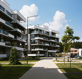 Modernos edificios de apartamentos con balcones, rodeados de vegetación y un sendero para caminar. El cielo azul con algunas nubes de fondo, ofrece un escenario perfecto para gestión inmobiliaria en Palma de Mallorca.